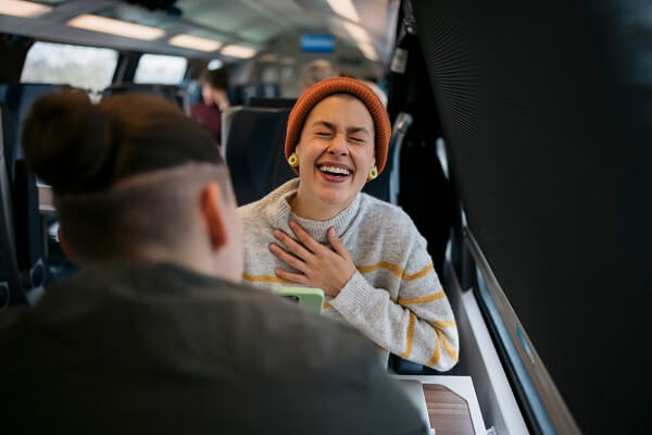 Two Women On Train Laughing Orange Hat