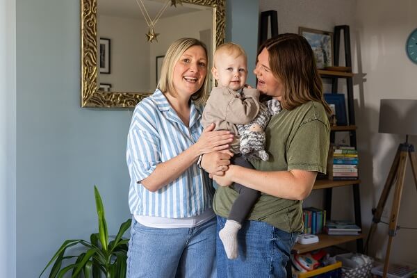 Women Holding Young Child Smiling Stripey Shirt