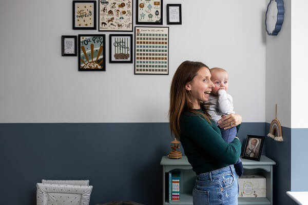 Woman Looking Out Of Window Holding Baby