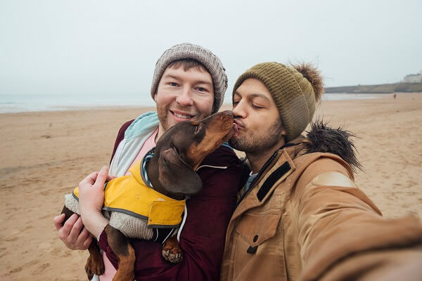 Couple On Beach Kissing Dog