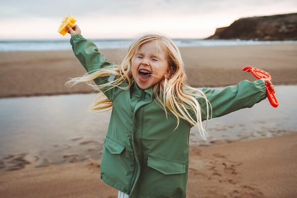 Child On Beach Eyes Shut Arms In Air