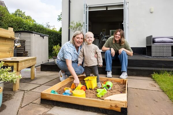 Women Playing With Baby In Sand Pit