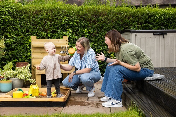 Couple Playing With Baby Outside Sand Pit